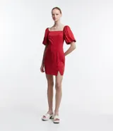 Vestido corto rojo con lunares blancos, escote cuadrado, mangas cortas abullonadas y abertura lateral en la falda.