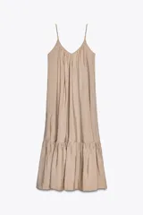 Vestido midi color beige de tejido fluido con escote pico, tirantes finos ajustables y bajo acabado en paneles con pliegues.