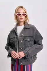 Campera de jean gris oscuro con cuello clásico, cierre frontal con botones metálicos, bolsillos con solapa en el pecho y corte holgado.