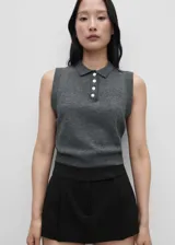 Chaleco gris de tejido de punto fino, con cuello camisero y cierre de botones. Sin mangas y de diseño recto.