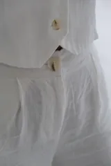 Pantalón palazzo color blanco hueso, de tiro alto y corte holgado. Confeccionado en lino.
