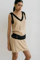 Minifalda color beige con detalle de volados negros en escote, cintura y sisas.