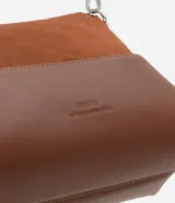 Cartera de hombro pequeña marca Satinato, color marrón, con diseño dividido en dos texturas: parte superior aterciopelada (suede sintético) y parte inferior lisa de cuero sintético. Cuenta con bolsillo delantero amplio, asa ajustable y desmontable con herrajes metálicos plateados, y cierre superior con cremallera y tirador alargado.