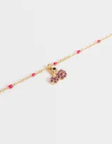 Collar corto dorado con cadena de eslabones y cuentas rosadas. Dije de cerezas con incrustaciones de strass fucsia y hoja verde.