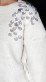 Buzo de punto color gris con escote redondo, corte clásico y detalle bordado de lentejuelas plateadas en el hombro.