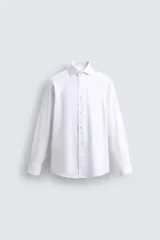 Camisa blanca de corte recto, con cuello italiano abierto, mangas largas con puños abotonados y cierre frontal con botones.