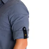 Camisa de manga larga color celeste, con cuello clásico, cierre frontal con botones y bolsillo en el pecho izquierdo con logo de la marca. Las mangas pueden enrollarse y sujetarse con una tira. Corte recto y dobladillo camisero.