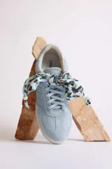 Zapatillas bajas de gamuza celeste con cordones y pañuelos estampados atados a los cordones.