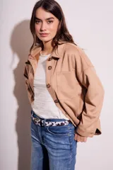 Sobrecamisa negra de gamuza vegana con calce oversize, cuello camisero, cierre con botones a presión, mangas largas con puños abotonados y bolsillos de parche en el pecho.