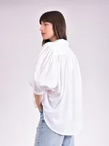 Camisa celeste con cuello mao, corte holgado, mangas 3/4 abullonadas con puños elásticos y cierre frontal con botones.