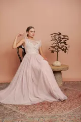 Vestido largo de fiesta color rosado con lunares blancos. Tiene cuerpo de micro tul bordado con volados en los hombros y falda de tul con forro. Incluye cinturón de raso al tono.