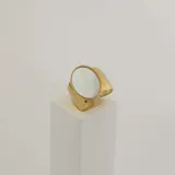 Anillo dorado con una piedra redonda de nácar.
