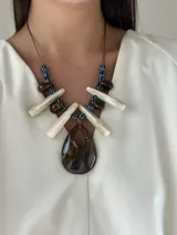 Collar largo con tiento sintético ajustable, cuentas de cerámica y medallones grandes de resina color marrón, blanco y azul.
