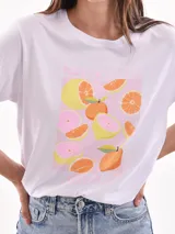Remera color amarillo claro con estampado de limones, hojas y flores en tonos verdes y grises.