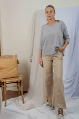 Pantalón de mujer color beige, tiro alto, de corte acampanado y con abertura frontal en el ruedo.