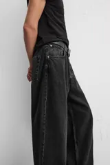Pantalón de jean negro de corte amplio, con cinco bolsillos, efecto lavado y cierre frontal con cremallera y botón.