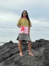 Poncho corto con capucha, color verde oliva con detalles en rosa y gris.