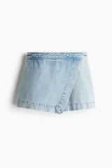 Short pollera de jean celeste, de corte evasé con frente cruzado cosido y cierre trasero oculto.