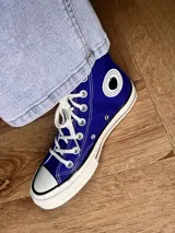 Zapatillas de lona blancas de caña alta con cordones y puntera de goma. Logo de durazno engomado en la base y en la cara interna.