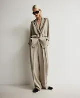 Pantalón de vestir color topo (beige grisáceo) de viscosa, corte barrel fit con cintura alta, doble pinza delantera y bolsillos de vivo en espalda. Presenta un detalle de pintura negra simulando costuras en laterales, cinturilla, pinzas y bolsillos.