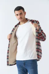Sobrecamisa de algodón para hombre con interior de corderito, estampado a cuadros en tonos negro, blanco y azul. Tiene cierre de botones, bolsillos tipo cartera y logo en goma. El modelo usa talle M.