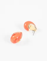 Par de aros colgantes color coral con forma de gota y borde dorado.
