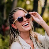 Lentes de sol Indie modelo Hill con montura redonda de madera color marrón y beige, y lentes grises degradadas.