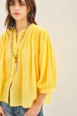 Camisa amarilla de algodón con corte amplio, cuello redondo y mangas 3/4 con puños elásticos.