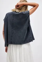 Remera estilo polo blanca de corte amplio con cuello clásico y botonadura corta en el frente. Tiene mangas cortas con dobladillo y aberturas laterales en el ruedo.