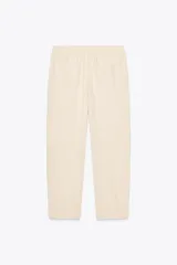 Pantalón bombacho color beige de lino, con cintura elástica, bolsillos frontales y bolsillos de parche en la espalda.