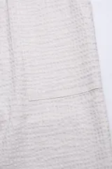 Pantalón color crema confeccionado en tejido ligero de algodón con textura tipo waffle. Presenta cintura elastizada con cordón de algodón ajustable, bolsillos laterales y bolsillo trasero.