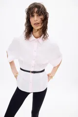 Camisa rosada de corte holgado, con cuello solapa, cierre frontal con botones y mangas cortas.