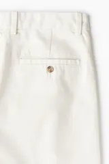 Pantalón de vestir color crema, de corte recto, con bolsillos laterales y traseros. Se ajusta a la cintura con botón.