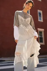 Vestido blanco de encaje con transparencias, breteles finos y volados en el ruedo.