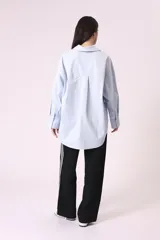 Camisa celeste de corte amplio, con cuello clásico, mangas largas y bolsillo en el pecho.