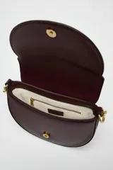 Bolso de hombro ovalado negro con asa de doble tira redonda con detalles metalizados dorados. Cierre imantado y asa de bandolera extraíble con tejido a contraste. Bolso interior con cierre mediante cremallera metálica.