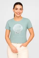 Remera de manga corta color verde agua, de algodón, con estampado de una concha marina plateada y texto en cursiva.