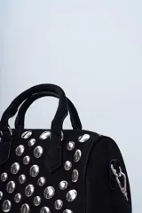 Cartera negra con tachas plateadas, doble asa corta y correa larga desmontable.