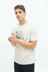 Remera color crema de manga corta con estampa fotográfica de un pueblo costero.