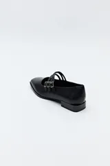 Zapato tipo Mary Jane color negro con textura de reptil, de charol sintético con punta cuadrada y triple tira con hebillas.