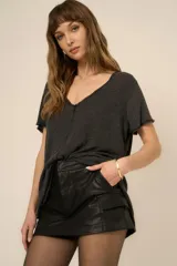 Remera gris oscuro de poliéster y algodón, con escote en V, corte holgado, bordes sin rematar, costura central expuesta y dobladillo estilo camisa.