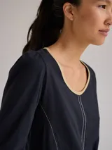 Remera blanca de algodón con escote redondo, mangas largas y pespuntes verticales a contratono.