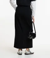 Falda midi de sastrería color negro, con trabillas en la cintura, cierre con botón y cremallera, y abertura delantera.