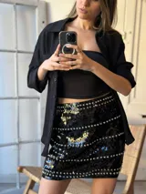Minifalda negra de lentejuelas con tachas plateadas y cintura elastizada.