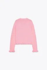 Chaqueta de punto rosa con cuello redondo y manga larga. Detalle de volantes en los bordes y cierre frontal con botones.