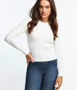 Blusa de punto color blanco con textura de ondas, cuello redondo y mangas largas.