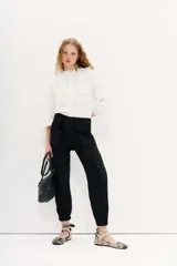 Pantalón cargo negro de corte relajado con ajuste en los tobillos, bolsillos laterales con solapa, cintura con botón y cierre, y elástico en la espalda.