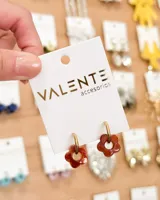 Aros colgantes con forma de flor color marrón con centro dorado, unidos a un aro dorado de acero.