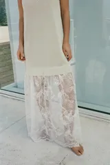 Vestido largo color beige, de punto fino, con escote en V y tirantes finos. La parte inferior es de encaje blanco.