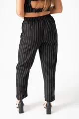 Pantalón palazo negro con cintura elástica, tiro alto y rayas verticales blancas.